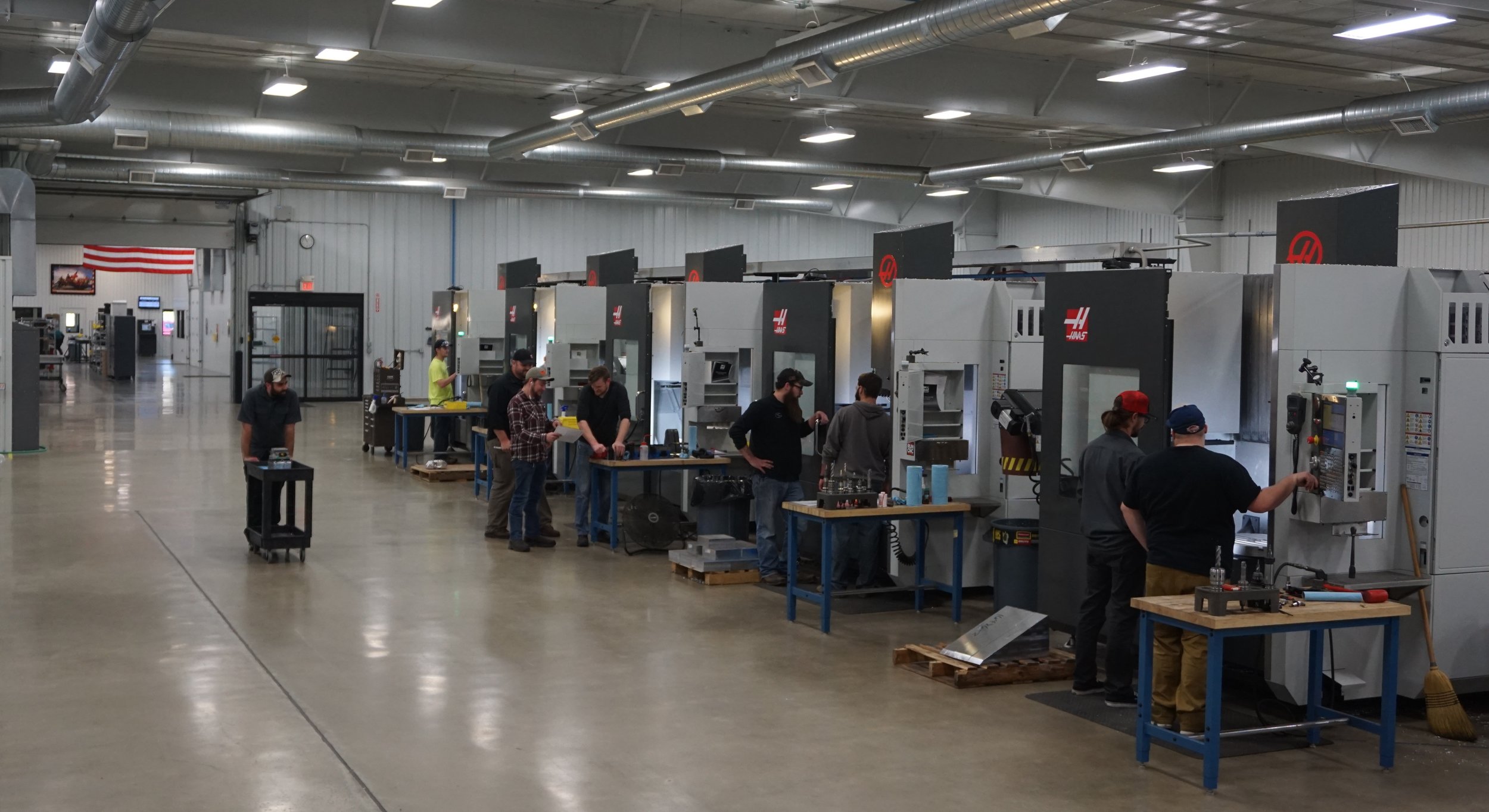 Haas CNC machines on the Flying S aerospace shop floor, with an American flag